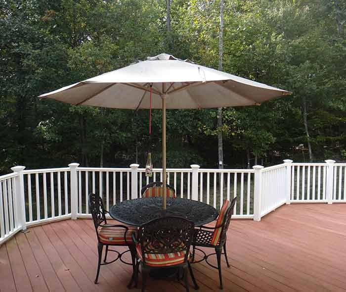 An outdoor deck with a table, umbrella and four chairs.