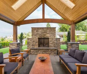 An outdoor fireplace with comfortable seating contained under a vaulted ceiling porch with skylights.